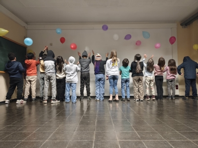 SchülerInnen stehen mit dem Rücken zur Kamera und werfen Luftballons hoch
